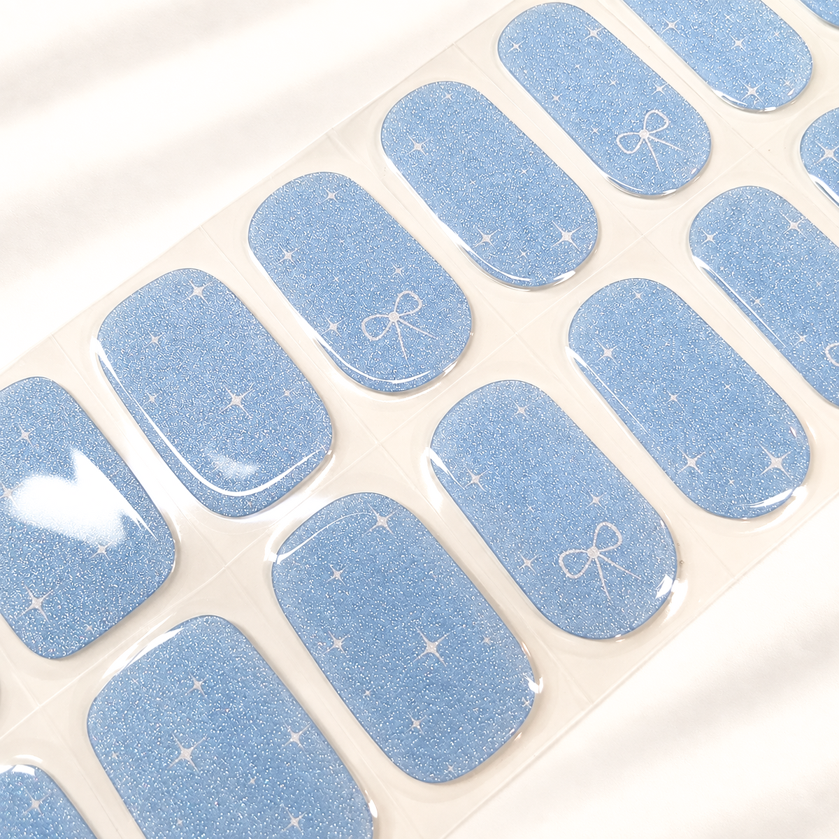 Aqua Twinkle baby blue semi-cured gel nail strips with subtle shimmer, twinkle and ribbon details by LAVU
