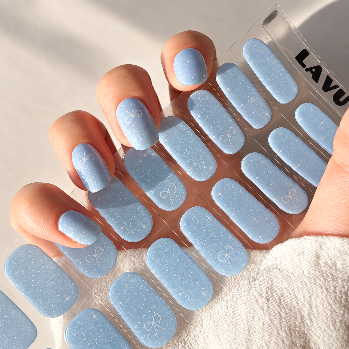 Aqua Twinkle baby blue semi-cured gel nail strips with subtle shimmer, twinkle and ribbon details by LAVU